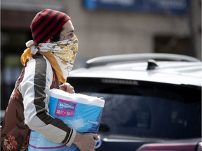 A man uses a scarf to cover his face while walking in Montreal on April 24, 2020 during COVID-19 crisis.
