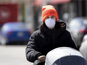 A woman wears a mask while pushing a stroller in Montreal on April 24, 2020, during COVID-19 crisis.