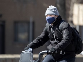 A person wears a mask while riding a bike in Montreal on April 24, 2020, during the COVID-19 crisis.