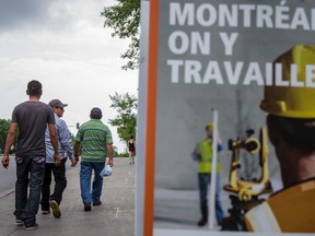 Latin American migrant workers who labour in Quebec farms walk past a sign reading "We work on Montreal" in 2015.