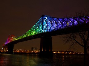 The Jacques Cartier bridge is lit up in the colours of the rainbow as a sign of solidarity and hope, seen through the city with the "ça va bien aller" rainbow drawings as the city deals with the coronavirus pandemic in Montreal, on Thursday, April 2, 2020.
