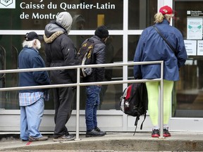 Not respecting guidelines on social distancing, customers crowd the entrance to a Desjardins branch on Berri St. in Montreal on Friday April 3, 2020.