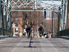 SPVM officers on bicycle patrol the now closed Charlevoix Bridge as the city deals with the coronavirus pandemic in Montreal, on Monday, April 6, 2020. The Atwater foot bridge was closed to foot traffic over the weekend, requiring pedestrians to detour to the Charlevoix Bridge which was closed to allow people to keep their distance while crossing the Lachine Canal.