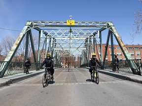 Montreal police officers on bicycle patrol the now-closed Charlevoix Bridge as the city deals with the coronavirus pandemic April 6, 2020. The Atwater foot bridge was closed over the weekend, requiring pedestrians to detour to the Charlevoix Bridge.
