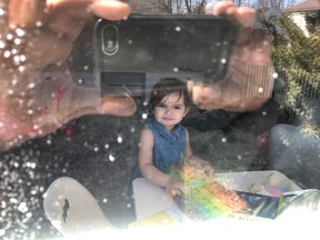 Mario Lorini of Dorval snaps a photo through a window of granddaughter Juliana, 2, opening a birthday present he had left at the door of her parents' home.