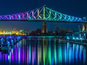 A section of the Jacques Cartier Bridge, illuminated in rainbow colours, is reflected in the St. Lawrence River in the Old Port on Saturday April 25, 2020.