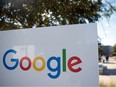 In this file photo taken on Nov. 4, 2016, a man rides a bike past a Google sign and logo at the Googleplex in Menlo Park, Calif.