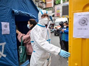 A man wearing a protective suit controls the access to a market in Wuhan, in China's central Hubei province on March 30, 2020, after travel restrictions into the city were eased following more than two months of lockdown due to the COVID-19 coronavirus outbreak.