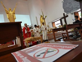 A priest prays before palm fronds during a mass ahead of the Palm Sunday celebration at a Roman Catholic church where the chairs are marked for social distancing as preventive measure to stem the spread of the COVID-19 coronavirus in Bangkok on Saturday, April 4, 2020.