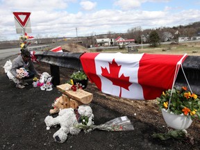 Krista Hughes adjusts flowers that had blown away from a makeshift memorial for Royal Canadian Mounted Police (RCMP) Constable Heidi Stevenson, who was shot dead during Sunday's killing spree that worked it's way across several Nova Scotian communities, in Shubenacadie, near Enfield, Nova Scotia, Canada April 22, 2020. REUTERS/Tim Krochak
