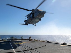 Air detachment members aboard HMCS Fredericton attach a fueling hose on the hoist cable of a CH-148 Cyclone helicopter during Operation Reassurance at sea February 15, 2020, in this picture obtained from social media. Picture taken February 15, 2020.
