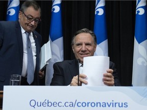 Quebec Premier François Legault gathers his papers at the end of a news conference on the COVID-19 pandemic on Friday, April 10, 2020, at the legislature in Quebec City. Horacio Arruda, Quebec director of National Public Health, left, looks on.