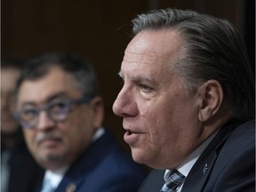 Quebec Premier François Legault speaks to reporters during a news conference on the COVID-19 pandemic on Friday, April 24, 2020, at the legislature in Quebec City. Horacio Arruda, Quebec director of National Public Health, left, looks on.
