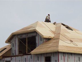 A construction worker stands on the roof of a house being built.