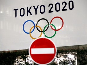 FILE PHOTO: A banner for the upcoming Tokyo 2020 Olympics is seen behind a traffic sign, following an outbreak of the coronavirus disease (COVID-19), in Tokyo, Japan, March 23, 2020.   REUTERS/Issei Kato -/File Photo ORG XMIT: FW1