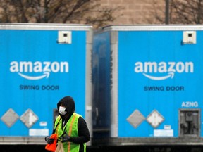 A worker in a face mask walks by trucks parked at an Amazon facility as the global coronavirus outbreak continued in Bethpage on Long Island in New York, U.S., March 17, 2020. REUTERS/Andrew Kelly/File Photo