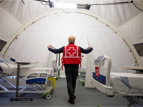 A volunteer with the Red Cross shows a doorway between beds in a mobile hospital set up at Jacques-Lemaire Arena to help care for patients with COVID-19 in April 2020.