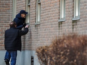 Pierre Boule (top) and his brother Sylvain look in a window to see their 96-year-old mother, Georgette Larame, at Centre d'hébergement Yvon-Brunet, a seniors' long-term care centre, amid the COVID-19 crisis in Montreal on April 16, 2020.