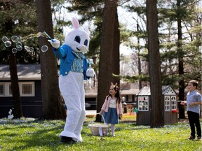 A person dressed as an Easter bunny blows bubbles with Genevieve Pina, 3, while making a surprise visit during a day full of Easter festivities amid the coronavirus outbreak in Plymouth, Mich., on Saturday, April 11, 2020.   In Zealnad, the Easter Bunnu has been declared an essential service, easing the fears of many boys and girls.