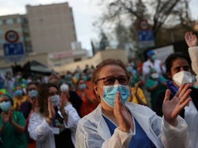 Medical staff from Gregorio Maranon hospital react as neighbours applaud from their homes in support for healthcare workers, amid the coronavirus disease (COVID-19) outbreak, in Madrid, Spain, April 6, 2020.