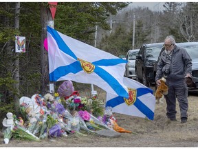 A man pays his respects at a roadside memorial in Portapique, N.S. on Thursday, April 23, 2020. RCMP say at least 22 people are dead after a man who at one point wore a police uniform and drove a mock-up cruiser, went on a murder rampage in Portapique and several other Nova Scotia communities.