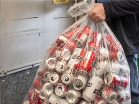 A Montreal dépanneur owner with a clear bag of recyclable cans.