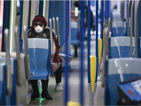 A woman wears a mask while sitting in a near-empty métro car leaving the Angrignon station March 16, 2020.