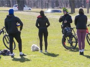 Montreal police officer issues a verbal warning to a group of friends at Jeanne Mance park Monday April 20, 2020. Some Montreal business and schools are set to reopen May 25.