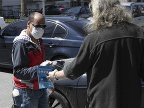 Richard Philoctete, left, give out mask and other safety measures to residents of Montreal North near Henri-Bourassa park on Saturday May 2, 2020.