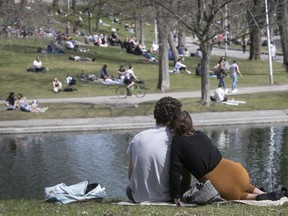 A Montreal couple watches the crowd at Lafontaine Park on a sunny Saturday, May 2, 2020.