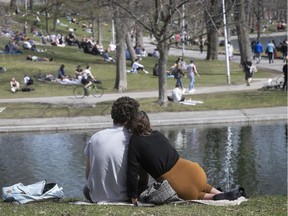 A couple enjoys the sunshine and watches the crowd at Lafontaine Park on May 2, 2020.