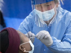 A healthcare worker administers a COVID-19 test at a mobile testing clinic in St-Michel.