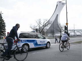 Cyclist pass next to a  Montreal police cruiser at the entrance of Maisonneuve park on Sunday May 3, 2020. The parking lot was closed to cars on Sunday to precent overcrowding of the nature park. (Pierre Obendrauf / MONTREAL GAZETTE) ORG XMIT: 64336 - 4662