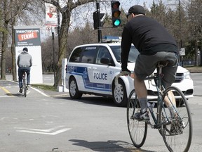 A cyclist passes next to a Montreal police cruiser at the entrance of Maisonneuve Park on Sunday May 3, 2020. The parking lot was closed to cars on Sunday to prevent overcrowding of the park.
