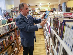 Ricardo Robles takes a book from shelf in the bookstore he owns in Granby, east of Montreal, on May 4, 2020 as stores outside of the greater Montreal area were allowed to open for the first time since the coronavirus lockdown.