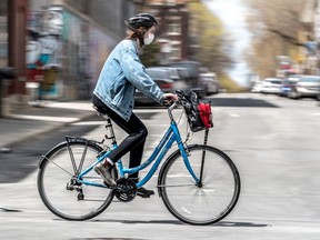 A woman wears mask while riding her bike on Montreal street during COVID-19 crisis on May 6, 2020.