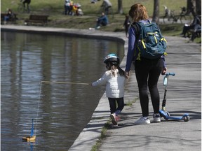 Florie Lagarde walks with her daughter Juliette, 4, pulling a wood model sailboat, during their morning walk at Lafontaine Park on Thursday, May 7, 2020.