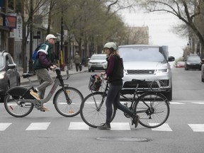 A couple of cyclists cross the street on St-Laurent Blvd. curing COVID-19 pandemic May 15, 2020. The city plans to reduce vehicle traffic on city streets to make them more pedestrian/cyclist friendly.