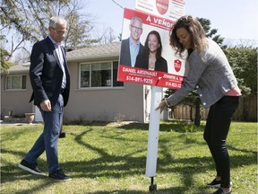 Dan Arsenault and Jennifer Smith, a husband and wife team who work for Royal Lepage Village in Pointe-Claire, place a for-sale sign on a front lawn earlier this month.