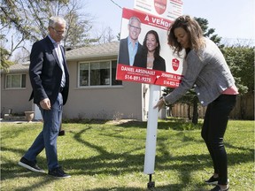 The husband and wife real estate team of Dan Arsenault and Jennifer Smith of of Royal Lepage Village in Pointe-Claire place a for-sale sign on a front lawn on May 14, 2020.