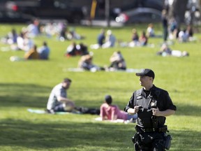 An SPVM officer keeps an eye on a busy Jeanne-Mance park in Montreal on May 18, 2020, during COVID-19 pandemic.