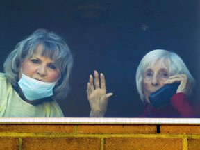 On her 100th birrhday and with her daughter Shirley Delage at her side, Brenda Roland waves while on the phone with husband Robert Côte, who is outside the CHSLD Saint-Lambert-sur-le-golf in Saint-Lambert.