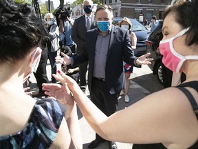 Quebec Premier François Legault takes his own advice regarding masks as he meets workers outside Coop Couturières Pop before his visit to the mask-making shop on Friday May 22, 2020.