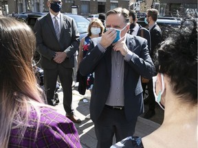 Quebec Premier François Legault adjusts his mask as he meets workers outside Coop Couturières Pop before his visit to the mask-making shop on Friday, May 22, 2020.