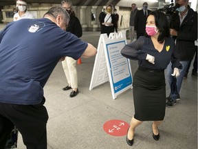 Montreal Mayor Valérie Plante steps back while giving an elbow greeting to an STM passenger. Plante was at Langelier métro station May 25, 2020, to give out face masks during the COVID-19 pandemic.