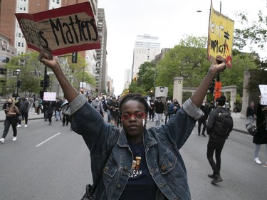 Protester holds up signs during an anti-racist and anti-police brutality demonstration on Sunday, May 31, 2020, in Montreal.