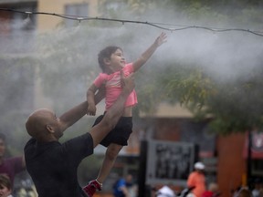 Anokhi Nandi's father, Arijit Nandi runs her through a misting area at Atwater Market in Montreal, on Monday, July 23, 2018.