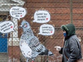 A pedestrian wearing a mask walks past art and words of thanks for frontline workers on Bloor Street West during the Covid 19 pandemic, Friday April 24, 2020.