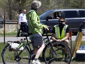 A cyclist speaks to a Kanesatake Mohawk at the entrance to Oka Park, where they have put up a blockade at the automobile entrance to the park near in Montreal on May 20, 2020. The cycling path remained opened. The cyclist continued in to the park without any further intervention by the Mohawks.