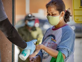 A customer gets a squirt of hand sanitizer as she enters a Metro grocery store in the Verdun borough of Montreal on May 21, 2020.